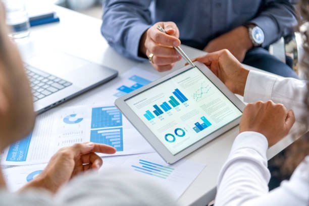 Two colleagues reviewing financial charts and dashboards on a tablet during a meeting